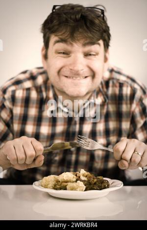 Ein Mann isst sein Mittagessen aus gebackenem Kaninchenfleisch und Gnocchi Stockfoto