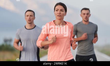 Eine Gruppe von Freunden, Athleten und Joggern nimmt die frühen Morgenstunden in Anspruch, während sie durch die nebelige Dämmerung laufen, die von der aufgehenden Sonne und angetrieben wird Stockfoto