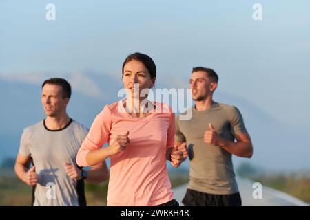 Eine Gruppe von Freunden, Athleten und Joggern nimmt die frühen Morgenstunden in Anspruch, während sie durch die nebelige Dämmerung laufen, die von der aufgehenden Sonne und angetrieben wird Stockfoto