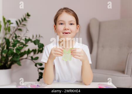 Glückliches kleines Mädchen, das zu Hause mit grünem Schleim spielt Stockfoto