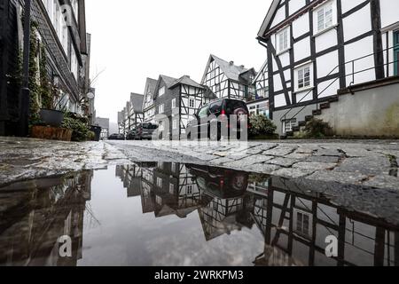 Schmuddeliges und ungemuetliches ungemütliches Wetter im Siegerland. Tristesse in der Altstadt von Freudenberg, ein beliebtes Touristenziel, Reiseziel in Südwestfalen Südwestfalen. Die Fachwerkhaeuser spiegelten sich in einer Pfuetze Pfütze Winter im Siegerland am 13.03.2024 in Freudenberg/Deutschland. *** Schmutziges und unangenehmes Wetter im Siegerland Tristesse in der Altstadt von Freudenberg, einem beliebten Touristenziel in Südwestfalen Südwestfalen die Fachwerkhäuser spiegeln sich in einer Wasserpfütze im Siegerland am 13 03 2024 in Freudenberg Stockfoto