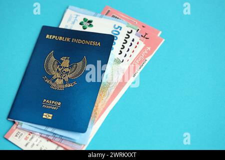 Blauer Indonesien Pass mit Geld und Flugtickets auf blauem Hintergrund Nahaufnahme. Tourismus und Reisekonzept Stockfoto