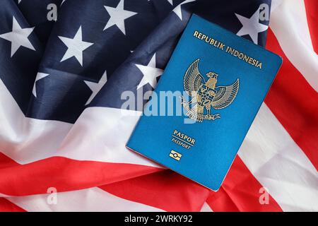 Pass der blauen Republik Indonesien auf dem Hintergrund der Nationalflagge der Vereinigten Staaten aus nächster Nähe. Tourismus und Diplomatie Stockfoto