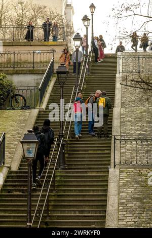 Paris, Frankreich - 17. Februar 2024 : Blick auf Touristen, die die malerischen Treppen mit Pariser Laternen im Montmartre Paris hinauf und hinuntergehen Stockfoto