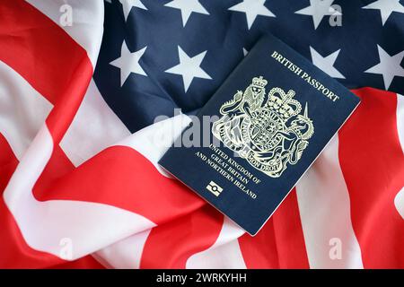 Blauer britischer Pass auf dem Hintergrund der US-Nationalflagge aus nächster Nähe. Tourismus und Diplomatie Stockfoto