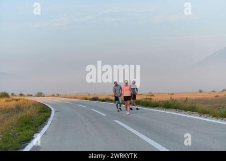 Eine Gruppe von Freunden, Athleten und Joggern nimmt die frühen Morgenstunden in Anspruch, während sie durch die nebelige Dämmerung laufen, die von der aufgehenden Sonne und angetrieben wird Stockfoto