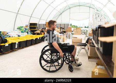 Ein behinderter Veteran im Rollstuhl hilft in einer humanitären Einheit. Unterstützung der Kriegsopfer. Stockfoto