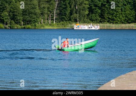 Aluksne, Lettland - 19. Juni 2021: Nicht identifizierte Menschen auf einem Motorboot auf dem See. Stockfoto