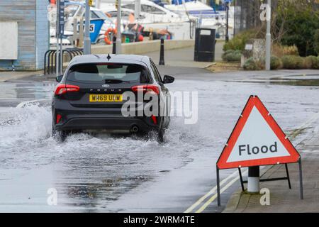 Weymouth, Dorset, Großbritannien. März 2024. Wetter in Großbritannien: Ein Auto fährt an einem warmen, bewölkten Morgen durch Hochwasser auf der Commercial Road neben dem Hafen von Weymouth in Dorset. Bildnachweis: Graham Hunt/Alamy Live News Stockfoto