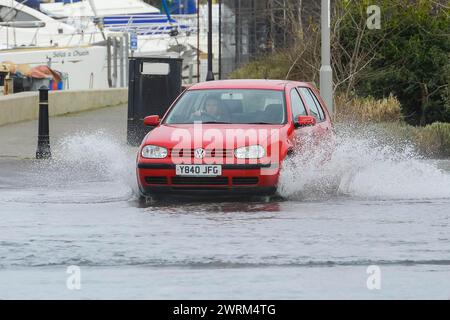 Weymouth, Dorset, Großbritannien. März 2024. Wetter in Großbritannien: Ein Auto fährt an einem warmen, bewölkten Morgen durch Hochwasser auf der Commercial Road neben dem Hafen von Weymouth in Dorset. Bildnachweis: Graham Hunt/Alamy Live News Stockfoto