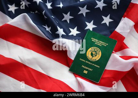 Grüner nigerianischer Pass auf dem Hintergrund der US-Nationalflagge aus nächster Nähe. Tourismus und Diplomatie Stockfoto