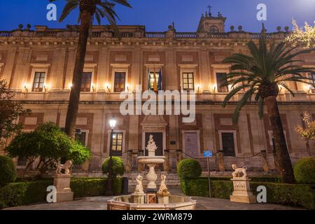 Archivo de Indias (Archivo de Indias) und Brunnen Fuente de Indias bei Nacht in Sevilla, Spanien. Spanische Renaissance Architektur f Stockfoto