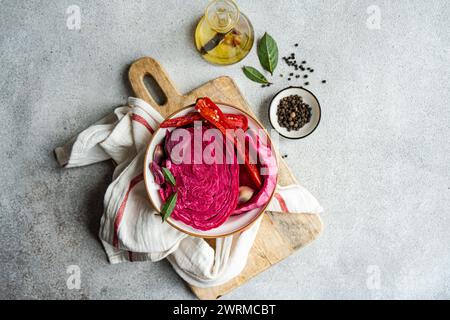 Lebendiger Rote-Bete-fermentierter Kohl mit scharfen roten Paprika und Knoblauch, serviert in einer Schüssel auf einem rustikalen Holzschneidebrett, begleitet von Olivenöl, Bucht Stockfoto