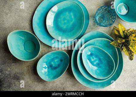 Blick von oben auf einen stilvollen Tisch mit hellen türkisfarbenen Keramikplatten, Schüsseln und Gläsern. Ideal für moderne Dining-Präsentationen. Stockfoto