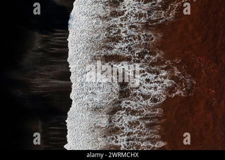 Die einzigartige rötliche Farbe des Wassers am Llumeres Beach, Asturien, ist von Eisenoxid aus alten Bergbauaktivitäten getönt. Stockfoto