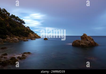 Lange Sicht fängt das ruhige Wasser und den Himmel in der Dämmerung entlang der malerischen Küste von Cala dels Frares in Katalonien, Spanien, ein. Stockfoto