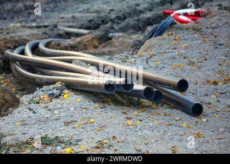 Verlegung von Kunststoff-Kommunikationsrohren auf der Baustelle von Straßenreparaturarbeiten. Ein Rohrbündel, das aus dem Boden ragt Stockfoto