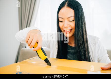 Eine Frau hält einen Universalschneider für präzises Auspacken und enthüllt Online-Shopping-Inhalte Stockfoto