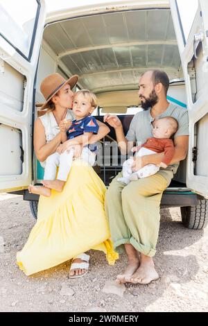 Eine Familie teilt einen zärtlichen Moment in einem alten Wohnmobil mit offenen Hintertüren zur Natur. Stockfoto