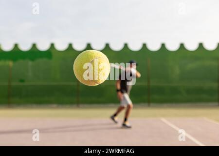 Der Tennisspieler hat während eines Rückhandschlags mitten in der Action aufgenommen. Konzentrieren Sie sich auf den Tennisball, während der Spieler im Hintergrund ist. Stockfoto