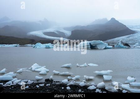 Ruhige Aussicht auf Eisberge, die sich in der Gletscherlagune am Fuße des Vatnajokull-Gletschers unter dem bewölkten isländischen Himmel bewegen Stockfoto