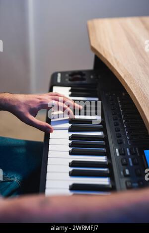 Abgeschnittene, nicht erkennbare Hände eines Musikers, der auf einer digitalen Tastatur spielt, um den kreativen Prozess einer Studio-Session festzuhalten. Stockfoto