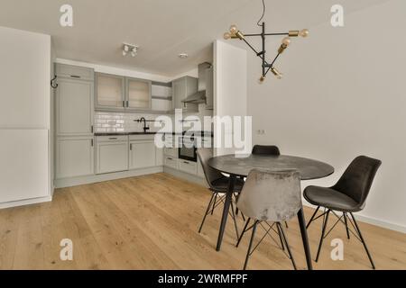 Eine Küche mit weißen Schränken und einem Tisch und Stühlen Stockfoto