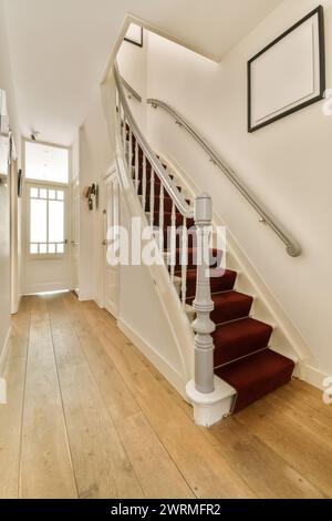 Ein gut beleuchteter Blick auf eine elegante Treppe mit roten Teppichstufen in einem hellen, modernen Innenraum, der eine Mischung aus Klassik und Moderne präsentiert Stockfoto