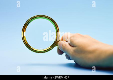 Männliche Hand mit blauem Lupenuntergrund Stockfoto