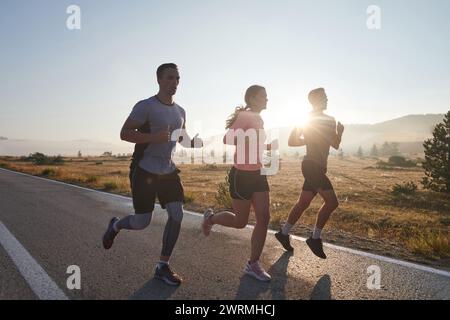 Eine Gruppe von Freunden, Athleten und Joggern nimmt die frühen Morgenstunden in Anspruch, während sie durch die nebelige Dämmerung laufen, die von der aufgehenden Sonne und angetrieben wird Stockfoto