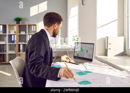 Der Katastervermesser arbeitet mit Stadtplänen und verwendet einen Laptop Stockfoto