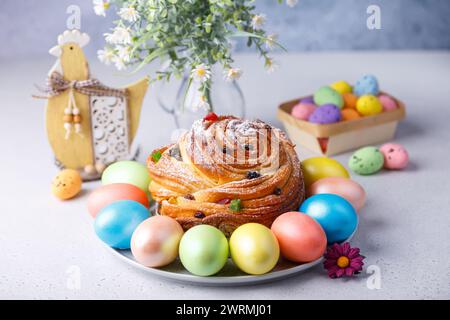 Craffin (Cruffin) mit Rosinen und kandierten Früchten mit Puderzucker. Traditionelles Osterbrot Kulich und bemalte Eier auf grauem Hintergrund Stockfoto