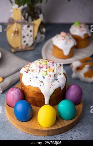 Osterkulich mit kandierten Früchten in weißer Glasur mit bunten Streuseln und bemalten Eiern. Traditionelles Ostergebäck. Osterferien. Nahaufnahme, wählen Sie Stockfoto