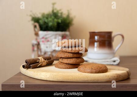 Haferflocken-Rosinenkekse auf einem Holzbrett mit Zimtstangen und einer Tasse Milch. Traditionelles hausgemachtes Gebäck im rustikalen Stil. Selektiver Fokus Stockfoto