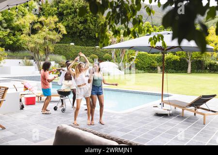 Verschiedene Gruppen von Freunden, die einen Grill am Pool genießen, mit Kopierbereich Stockfoto