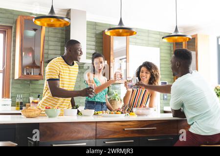 Eine Gruppe verschiedener Freunde genießt einen Toast in einer hellen Küche Stockfoto