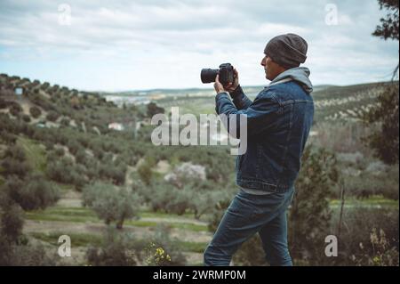 Landschaftsfotograf in Aktion, der Berge fotografiert. Kaukasischer junger Reisender, Wanderer, der die Schönheit der Natur und der Berge einfängt Stockfoto