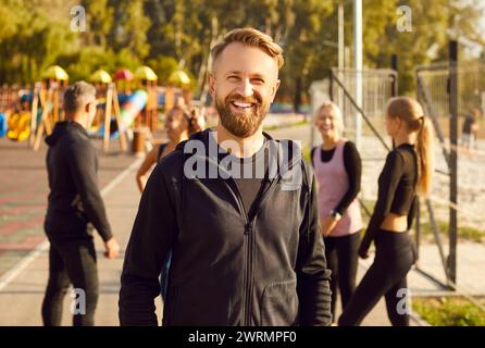 Porträt eines glücklichen sportlichen Mannes, der nach Fitnesstraining in der Natur im Park in die Kamera schaut. Stockfoto