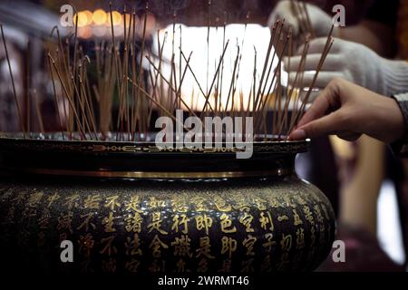 Menschen zünden Weihrauchstäbchen vor drei großen Statuen des Buddha an, wie es Tradition ist. Im chinesischen buddhistischen Tempel in Bronkhurstspruit, Stockfoto