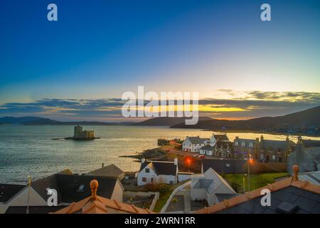 Blick auf den Sonnenuntergang über das Dorf Castlebay und Kisimul Castle, Isle of Barra, Äußere Hebriden, Schottland, Großbritannien Stockfoto