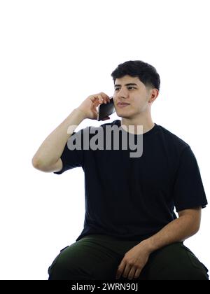 Studio-Bild eines jungen Mannes, der auf weißem Hintergrund sitzt und Freude beim Telefonieren ausdrückt Stockfoto