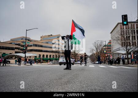 Washington, Usa. März 2024. Ein Demonstrant in der Mitte einer Kreuzung hebt während der Demonstration Pro-Palästina-Demonstranten, die sich vor der israelischen Botschaft in den Vereinigten Staaten versammelten, wo sich Aaron Bushnell vor einer Woche selbst anbrennte, eine palästinensische Flagge. Danach ging der marsch zum Haus des israelischen Botschafters. (Foto: Maria Giulia/SOPA Images/SIPA USA) Credit: SIPA USA/Alamy Live News Stockfoto