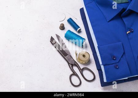 Stapel gefalteter langärmeliger Hemden, Garne, Scheren und anderer Werkzeuge für die Reparatur von Heimbekleidung mit Kopierraum Stockfoto