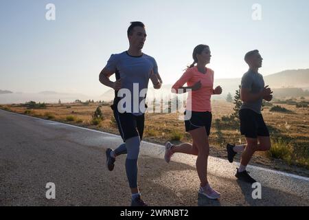 Eine Gruppe von Freunden, Athleten und Joggern nimmt die frühen Morgenstunden in Anspruch, während sie durch die nebelige Dämmerung laufen, die von der aufgehenden Sonne und angetrieben wird Stockfoto