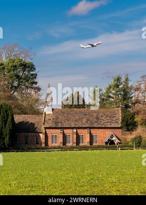 Norcliffe Chapel im Dorf Styal, mit einem großen Passagierflugzeug über dem Flughafen Manchester. UK Stockfoto