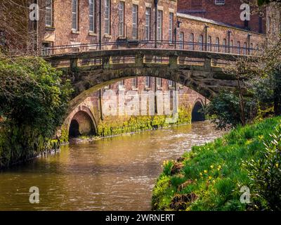 Packhorse Bridge überquert den Fluss Bollin mit Quarry Bank Mill dahinter. Styal, Cheshire. UK Stockfoto