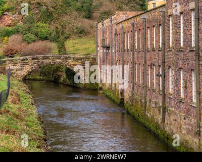 Packhorse Bridge überquert den Fluss Bollin mit Quarry Bank Mill auf der rechten Seite. Styal, Cheshire. UK Stockfoto