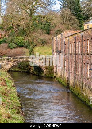 Packhorse Bridge überquert den Fluss Bollin mit Quarry Bank Mill auf der rechten Seite. Styal, Cheshire. UK Stockfoto