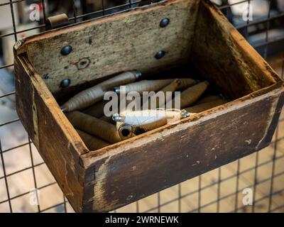 Pirnen aus natürlichem, ungefärbtem Baumwollfaden in einer Holzkiste. Stockfoto