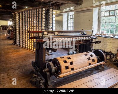 Wölbmaschine, die beim Weben von Baumwolle verwendet wird, mit Spulengestell dahinter. Quarry Bank Mill, Styal, Cheshire, Großbritannien Stockfoto